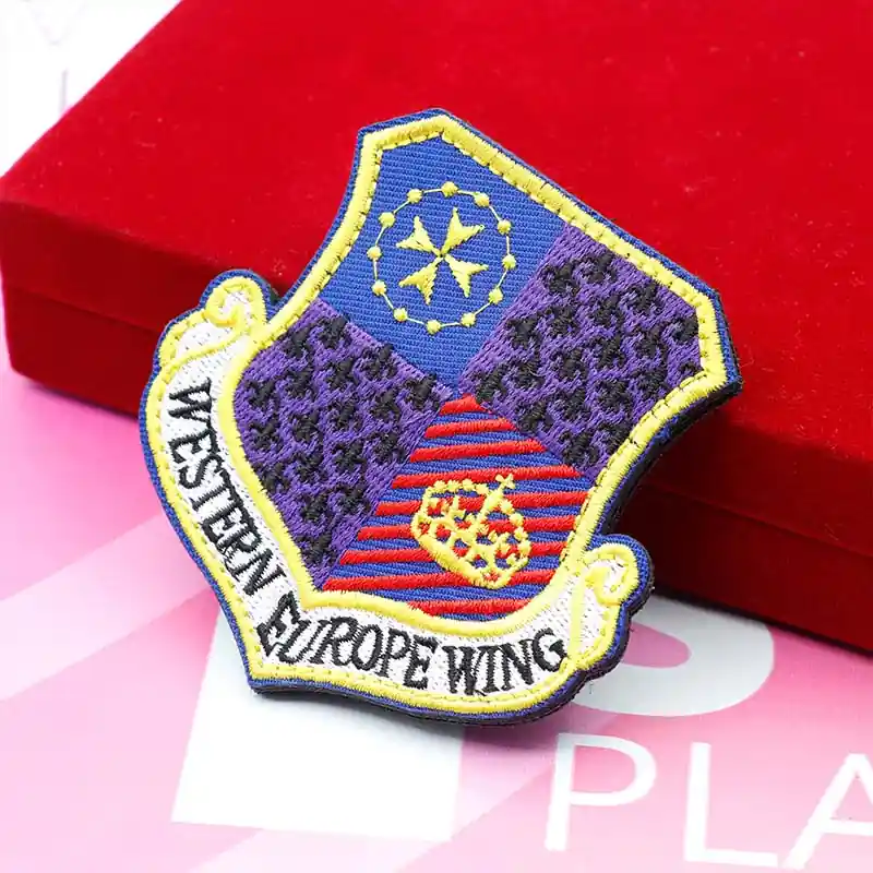 Colorful custom embroidered shield patch with “Western Europe Wing” text, detailed crest design, and decorative crown and star elements, displayed on a red box.