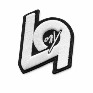 A black-and-white 3D embroidered patch featuring a stylized letter design with raised stitching, bold outlines, and a modern graphic look, isolated on a white background.