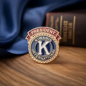 A gold and enamel lapel pin featuring the Kiwanis International logo with a red banner labeled President.