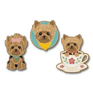 A set of three Yorkshire Terrier enamel pins including a sitting dog with a bow, a portrait with a yellow bandana, and a puppy in a floral teacup.
