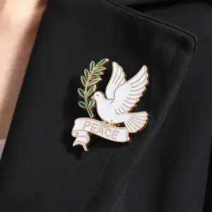 A white dove enamel pin with olive branch and peace banner attached to a black suit lapel.