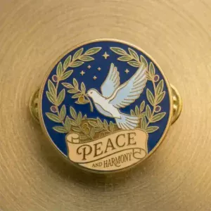 Round enamel lapel pin featuring a white dove holding an olive branch, surrounded by a laurel wreath on a deep blue background with stars and the words "Peace and Harmony" on a banner.