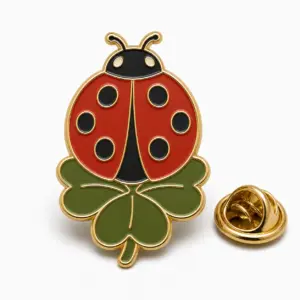 Ladybug clover enamel badge with attached clover leaf, metal-divided spots, and butterfly clutch on white background.