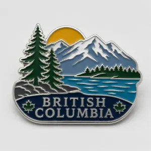 Mountain lake British Columbia enamel pin with silver metal outline, evergreen trees, snow capped mountains, blue lake, golden sun, maple leaves, and British Columbia lettering on a white background.