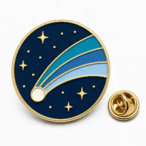 Round comet trail enamel badge with navy sky, segmented blue tail bands, gold dividers, stars, and butterfly clutch.