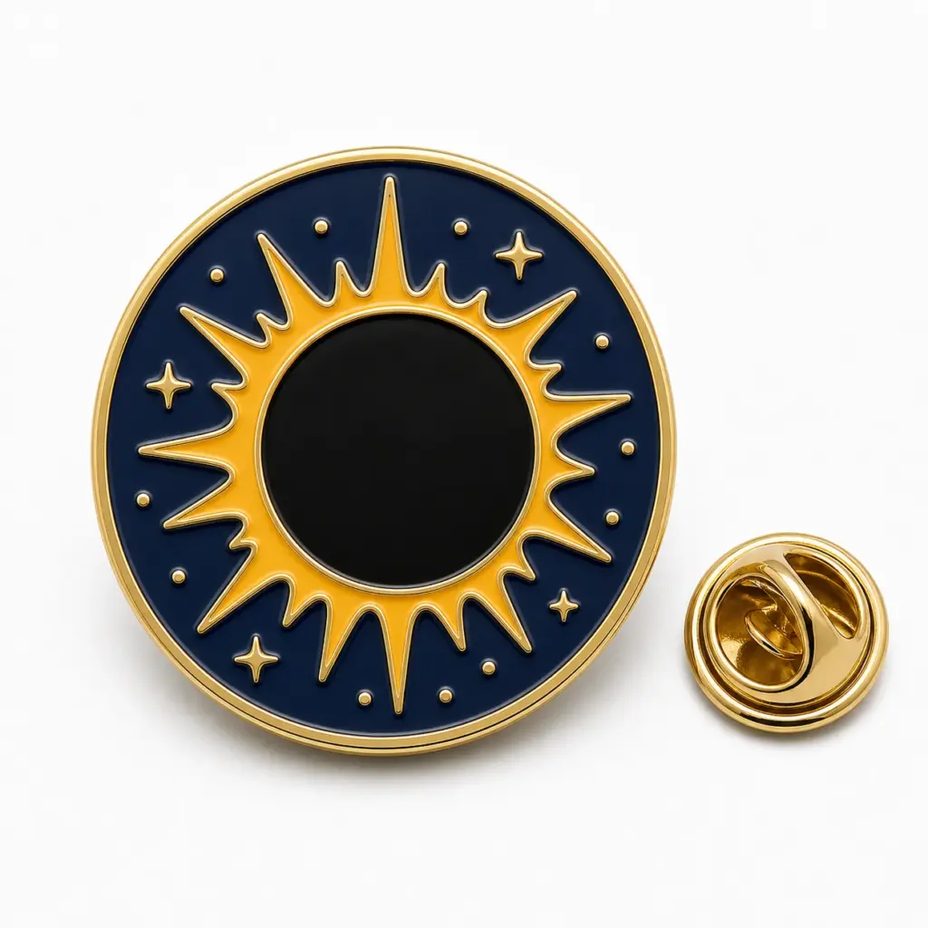 Badge rond en émail de l'éclipse solaire avec disque lunaire noir, couronne dorée, ciel bleu marine, séparateurs en relief et pochette papillon.