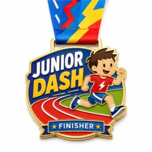 Cartoon runner track Junior Dash Medal soft enamel medal with raised gold outlines, blue and yellow lettering, red running track, green field, ribbon loop, and colorful neck ribbon on a white background.