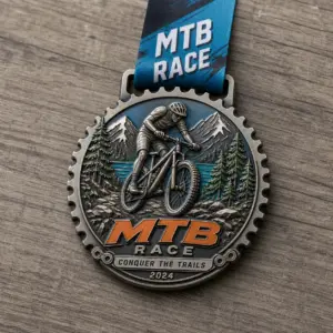 Gear edge mountain rider MTB Race Medal soft enamel medal with raised metal outlines, bicycle gear border, mountain biker, pine trees, rocky trail, and ribbon.