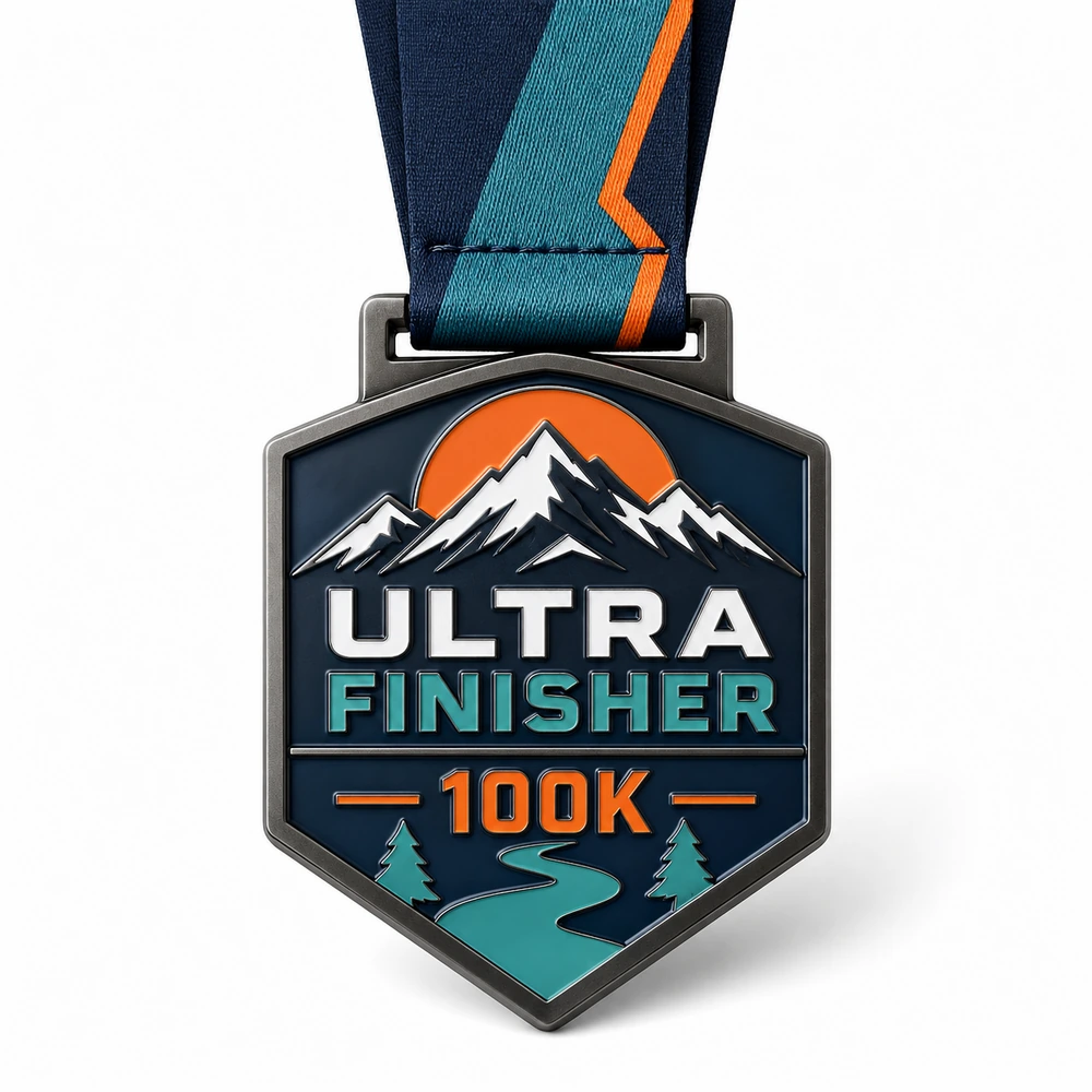 Sunset summit shield Ultra Finisher Medal soft enamel medal with raised dark metal outlines, snowy peaks, orange sun, teal river trail, pine trees, 100K text, and ribbon.