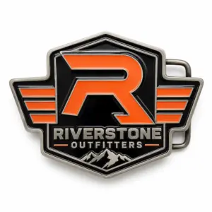 Hebilla de cinturón con el logotipo de Riverstone Outfitters: emblema «R» naranja, fondo esmaltado en negro, letras en relieve plateadas, detalle de montaña, alas a los lados y fondo blanco.